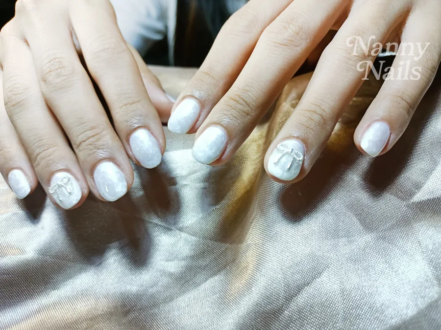 Soft milky white gel nails with a tiny silver bow on two nails, Nanny Nails, nail salon in Nakhon Phanom