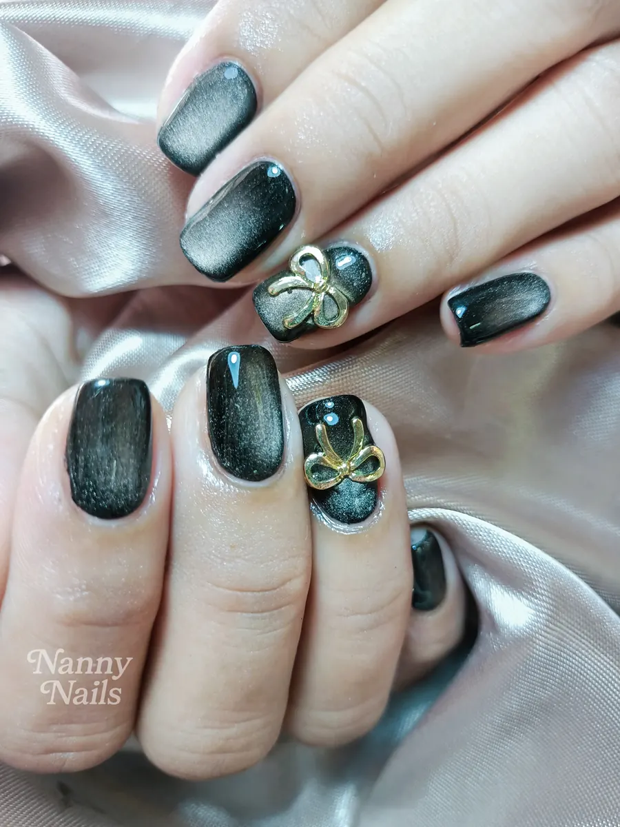 Black cat eye nails with a gold bow, Nanny Nails, nail salon in Nakhon Phanom