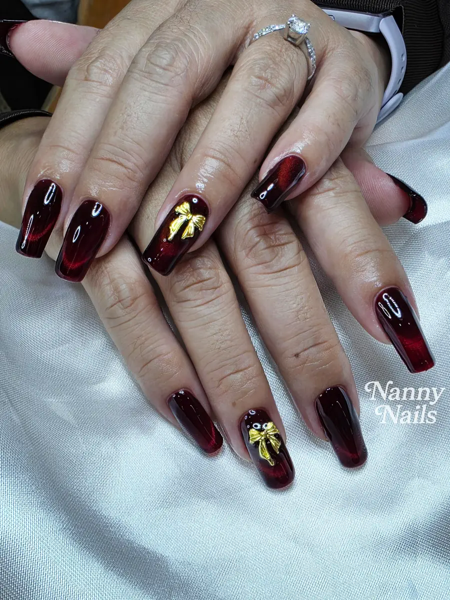 Wine red cat eye nails with gold bows, Nanny Nails, nail salon in Nakhon Phanom