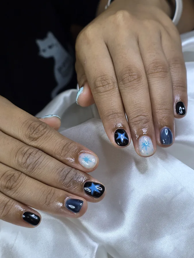 Short nails in black and navy with a few painted stars, a cool look on a female customer, Nanny Nails Nakhon Phanom
