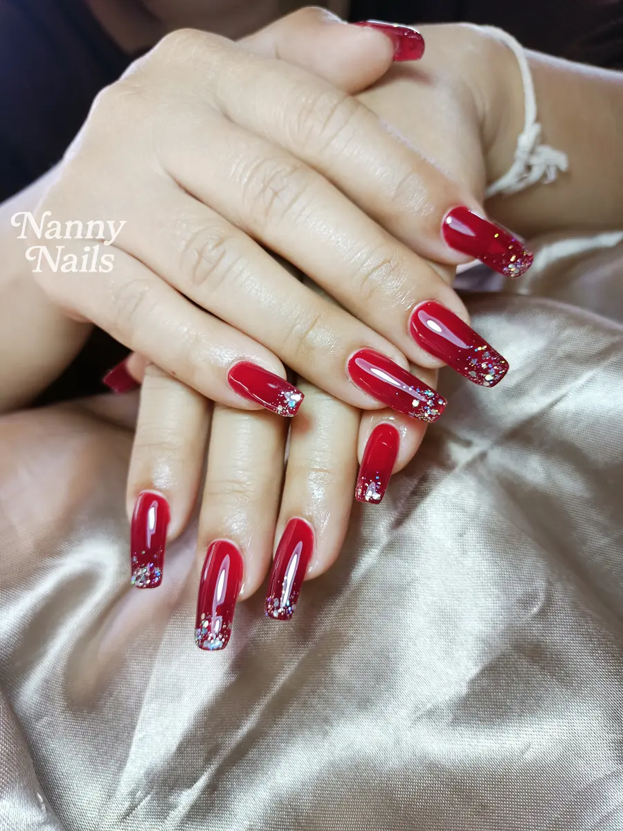 เล็บสีแดงเงาฉ่ำ ปลายเล็บโปรยกลิตเตอร์เงิน ทรงเหลี่ยมยาว ร้านทำเล็บนครพนม Nanny Nails