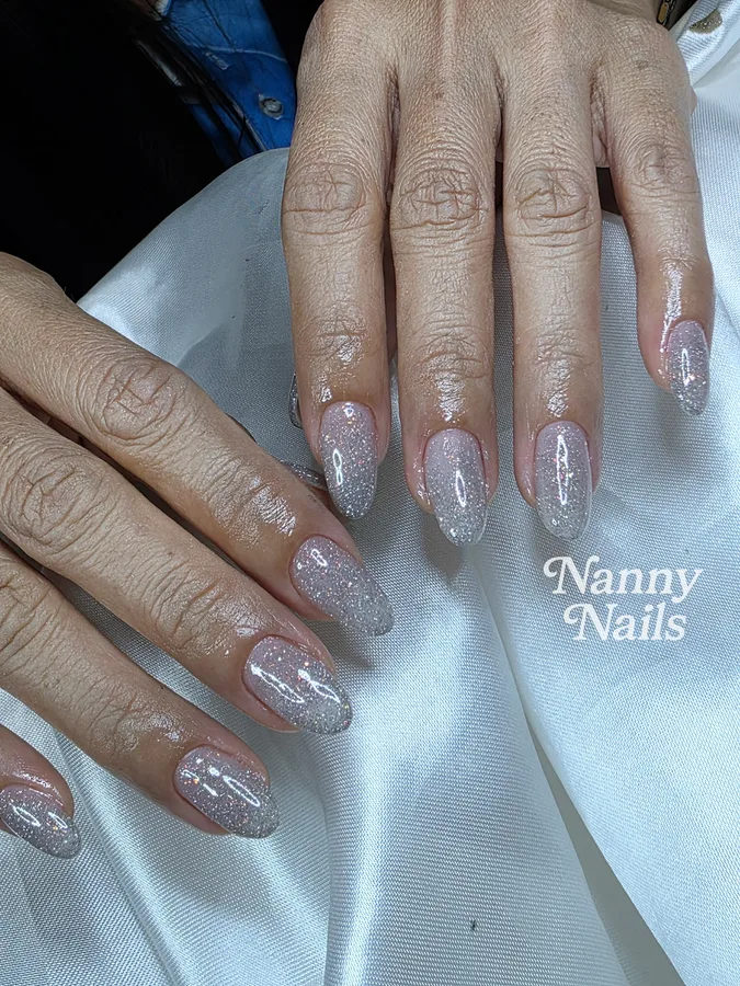 Silver glitter gel nails on a nude base, the sparkle draws the eye away from small marks, Nanny Nails Nakhon Phanom