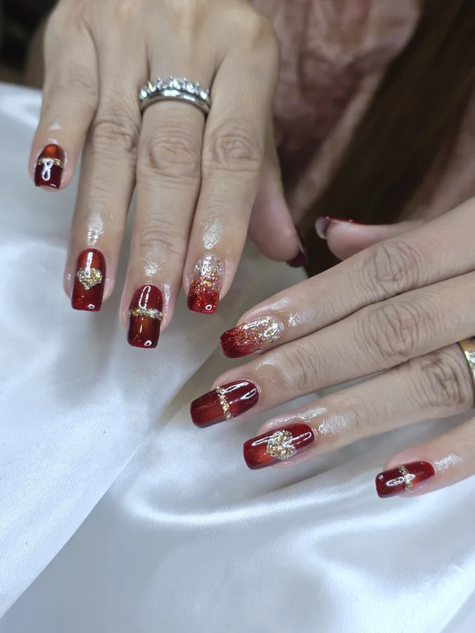 Square nails in red with a glitter fade and gold charms, Nanny Nails Nakhon Phanom