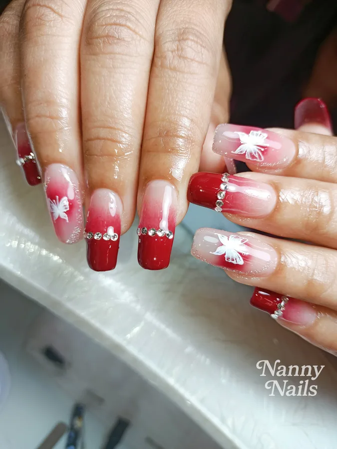 Red ombre nails with solid red nails, painted butterflies and rhinestones, Nanny Nails, nail salon in Nakhon Phanom