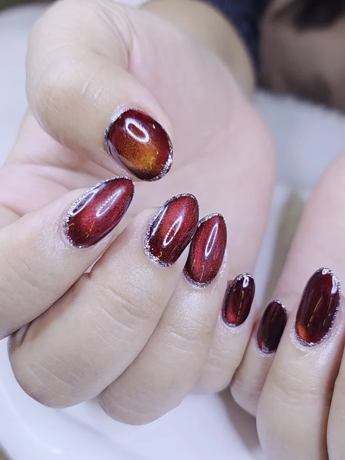 เล็บลูกแก้วสีแดงไวน์เหลือบทอง ทรงอัลมอนด์ ขอบเงา ร้านทำเล็บนครพนม Nanny Nails