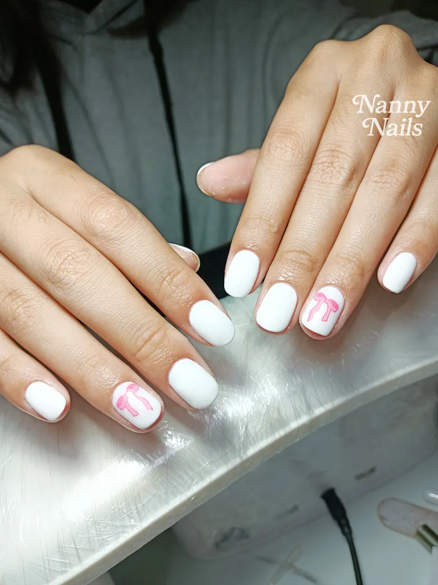เล็บสั้นสีขาวนวล แต่งโบว์ชมพู ทรงสแควร์ขอบมน ร้านทำเล็บนครพนม Nanny Nails