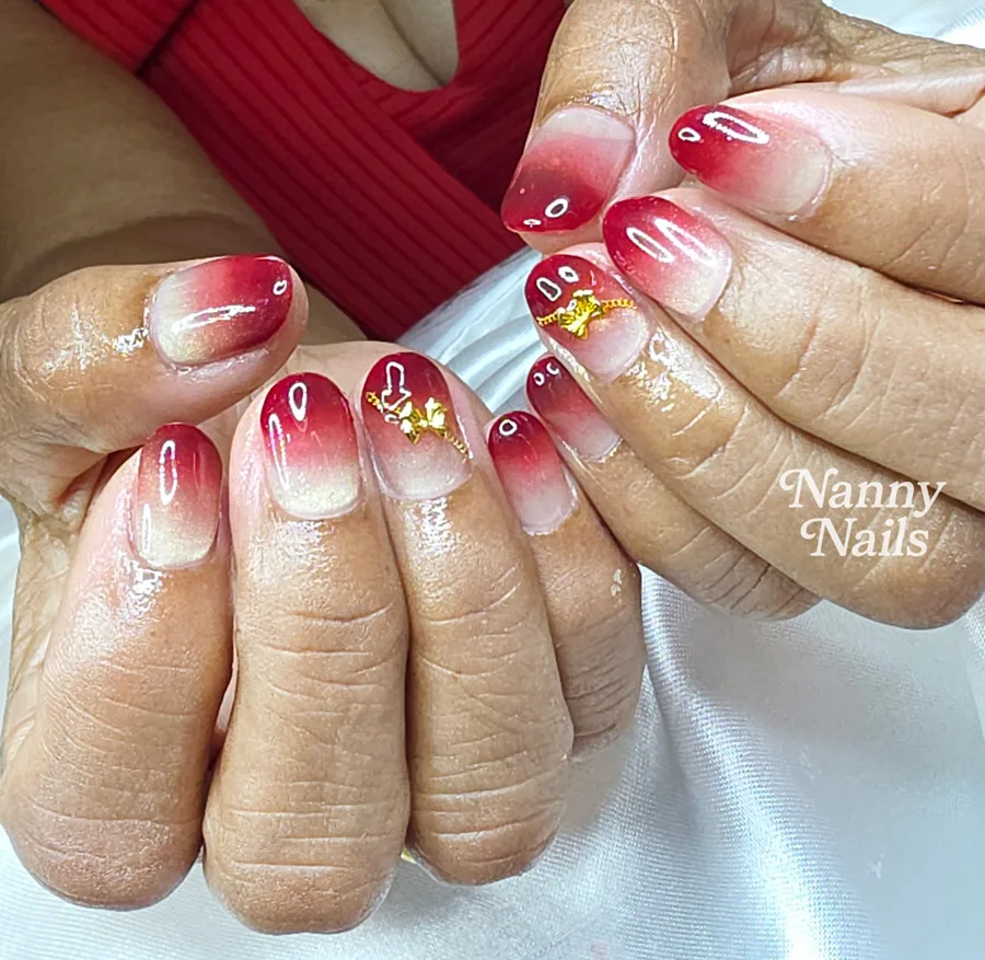Red ombre nails with gold charms worn with a red outfit, Nanny Nails, nail salon in Nakhon Phanom