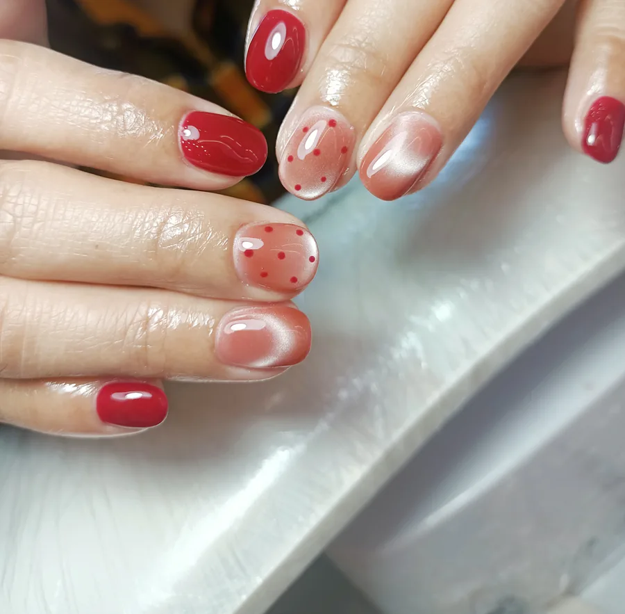 Red gel nails alternating with nude cat eye nails and tiny painted red dots, Nanny Nails Nakhon Phanom